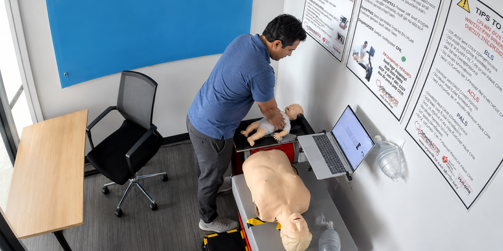 Participant practicing infant CPR chest compressions on an infant manikin at a Citywide CPR simulation station in Austin, Texas, with an adult CPR manikin and laptop visible.