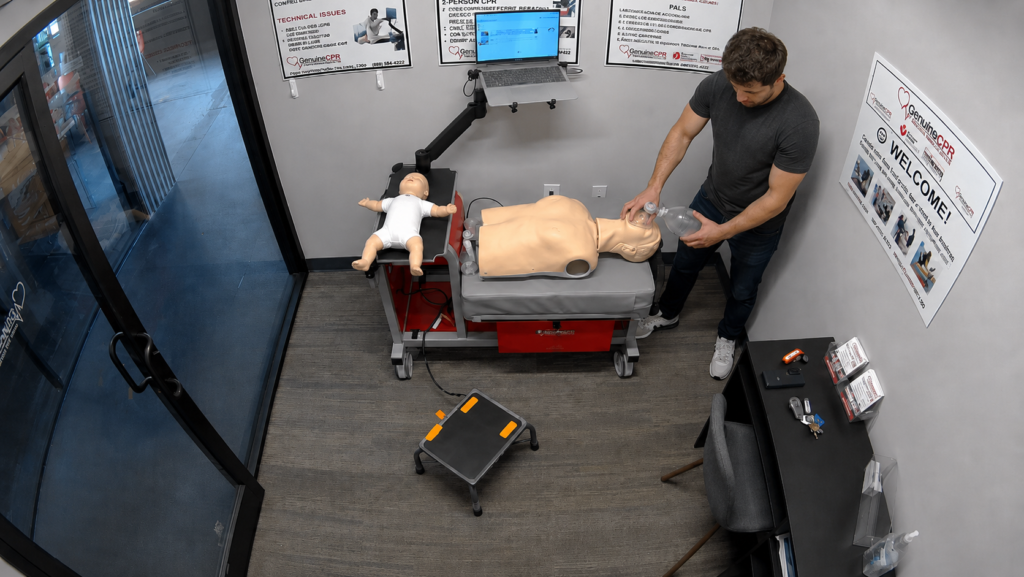 Participant providing bag-valve-mask ventilation to an adult CPR manikin at a Citywide CPR simulation station in Cleveland, Ohio, with a laptop and infant manikin in a white onesie visible.