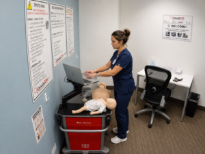 Healthcare professional performing CPR on an adult manikin during an American Heart Association BLS skills session.