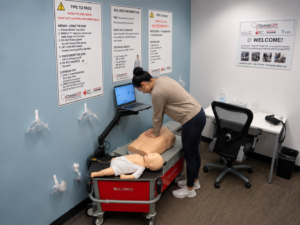 Healthcare professional completing hands-on resuscitation skills with an adult CPR manikin during an ACLS skills session.