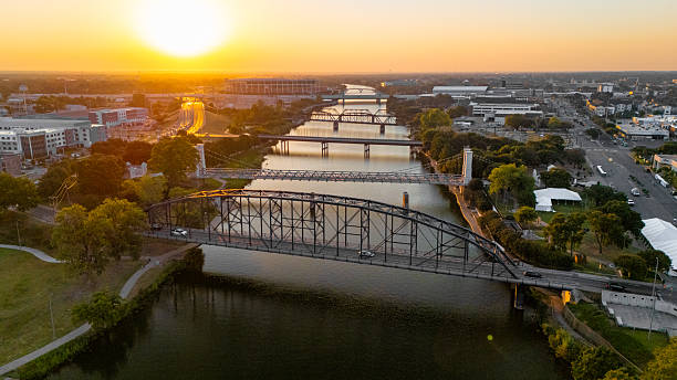 Aerial sunset view of the Brazos River and multiple bridges in Waco, Texas.